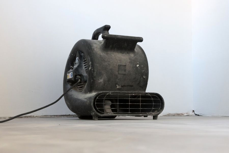 Industrial air mover positioned on a concrete floor during the active drying phase of water damage restoration